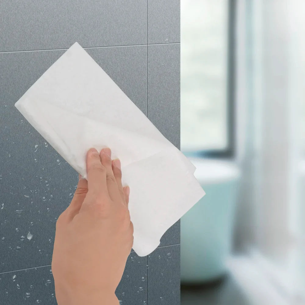 EcoNest Kitchen's roll of 25 reusable bamboo cleaning cloths next to a kitchen sink with soapy dishes