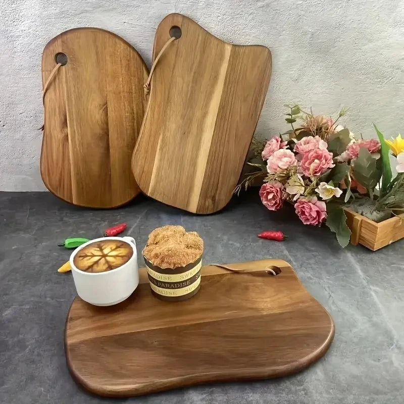 Wooden cutting boards on a gray surface with a cup of coffee and cookies, and flowers in the background.