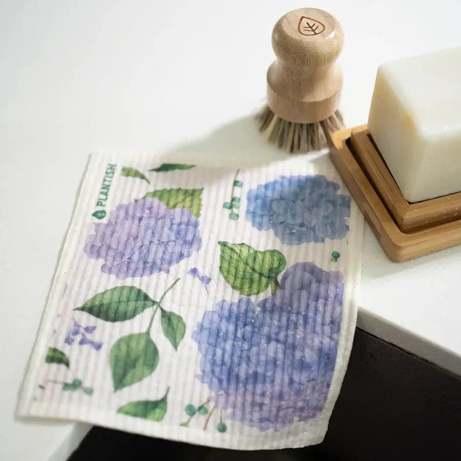 Wet wipes with floral design, wooden brush, and soap on a white surface