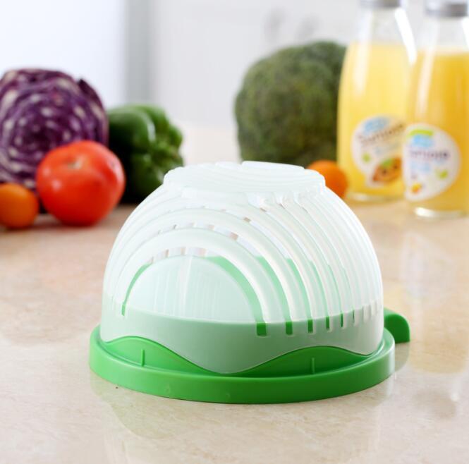 Green and white kitchen tool on a table with vegetables and juice in the background