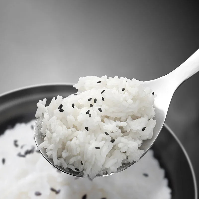 Spoonful of white rice with black sesame seeds on a dark background