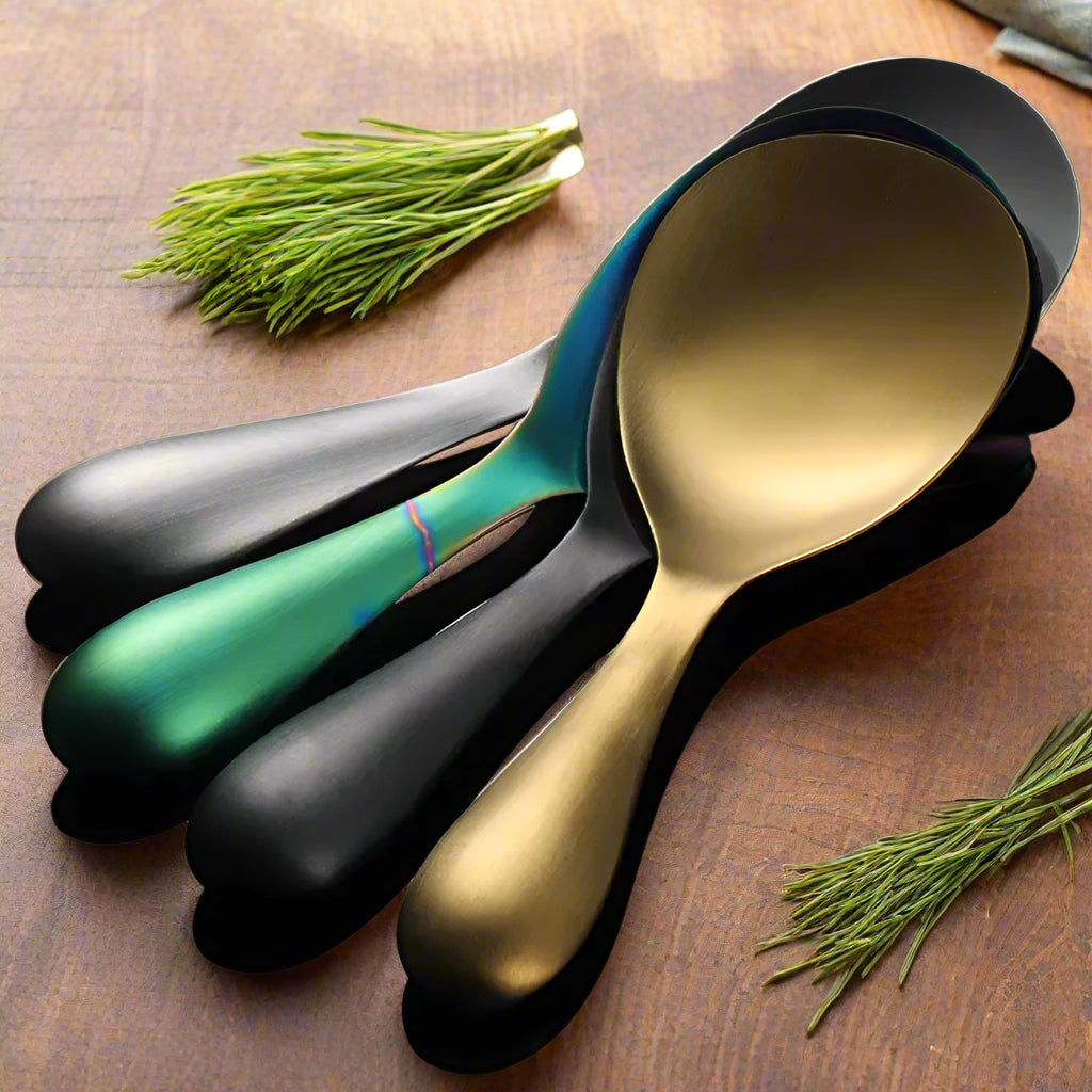 Set of four spoons in gold, silver, green, and black on a gray background