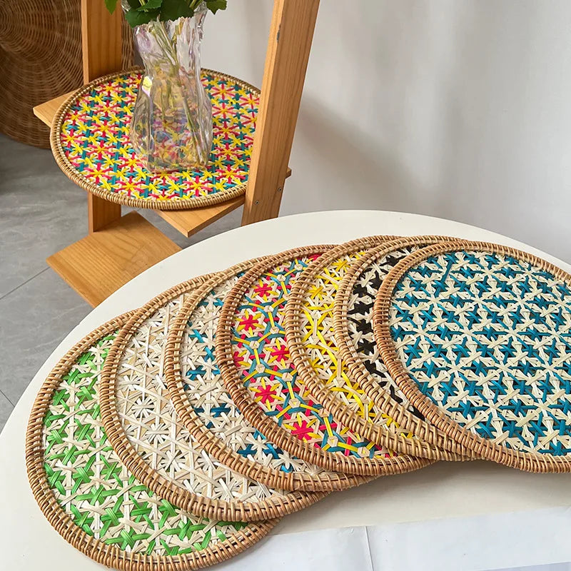 Set of colorful woven placemats on a white surface with a wooden chair in the background.
