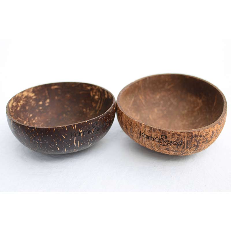 Four handcrafted coconut bowls on a natural wooden surface, surrounded by fresh tropical fruits. Each bowl has a smooth, polished finish with no branding or logo. Earthy and minimal.
