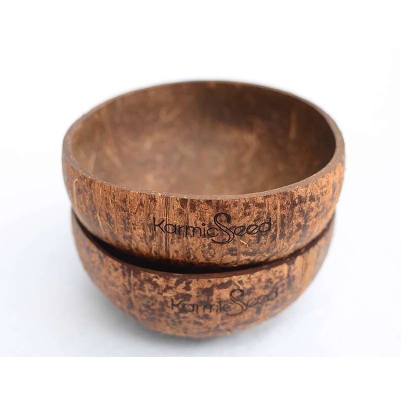 Four handcrafted coconut bowls on a natural wooden surface, surrounded by fresh tropical fruits. Each bowl has a smooth, polished finish with no branding or logo. Earthy and minimal.