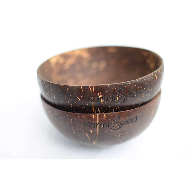 Four handcrafted coconut bowls on a natural wooden surface, surrounded by fresh tropical fruits. Each bowl has a smooth, polished finish with no branding or logo. Earthy and minimal.