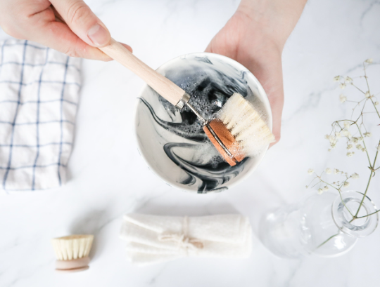 Person holding a marble-patterned soap with two brushes inside, on a light background.