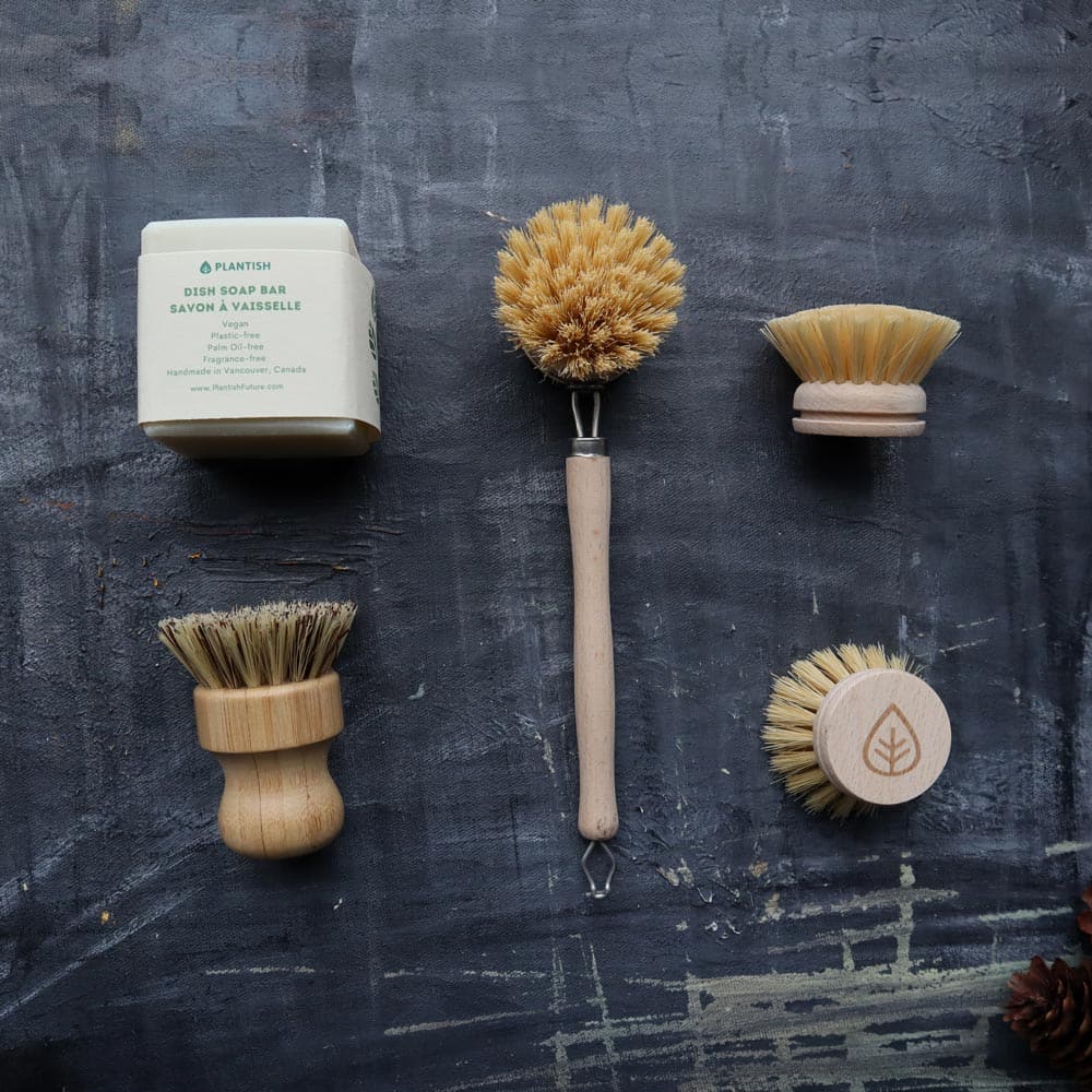 Set of natural cleaning brushes and soap bar on a textured dark surface