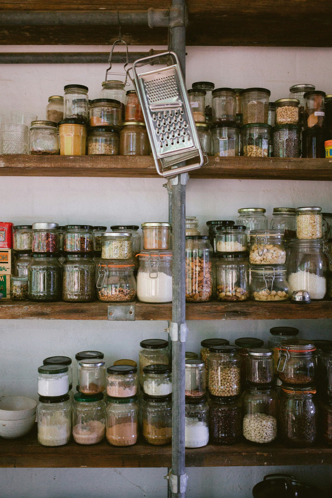 Sustainable eco-friendly kitchen pantry with glass storage jars containing bulk foods on wooden shelves - zero waste living