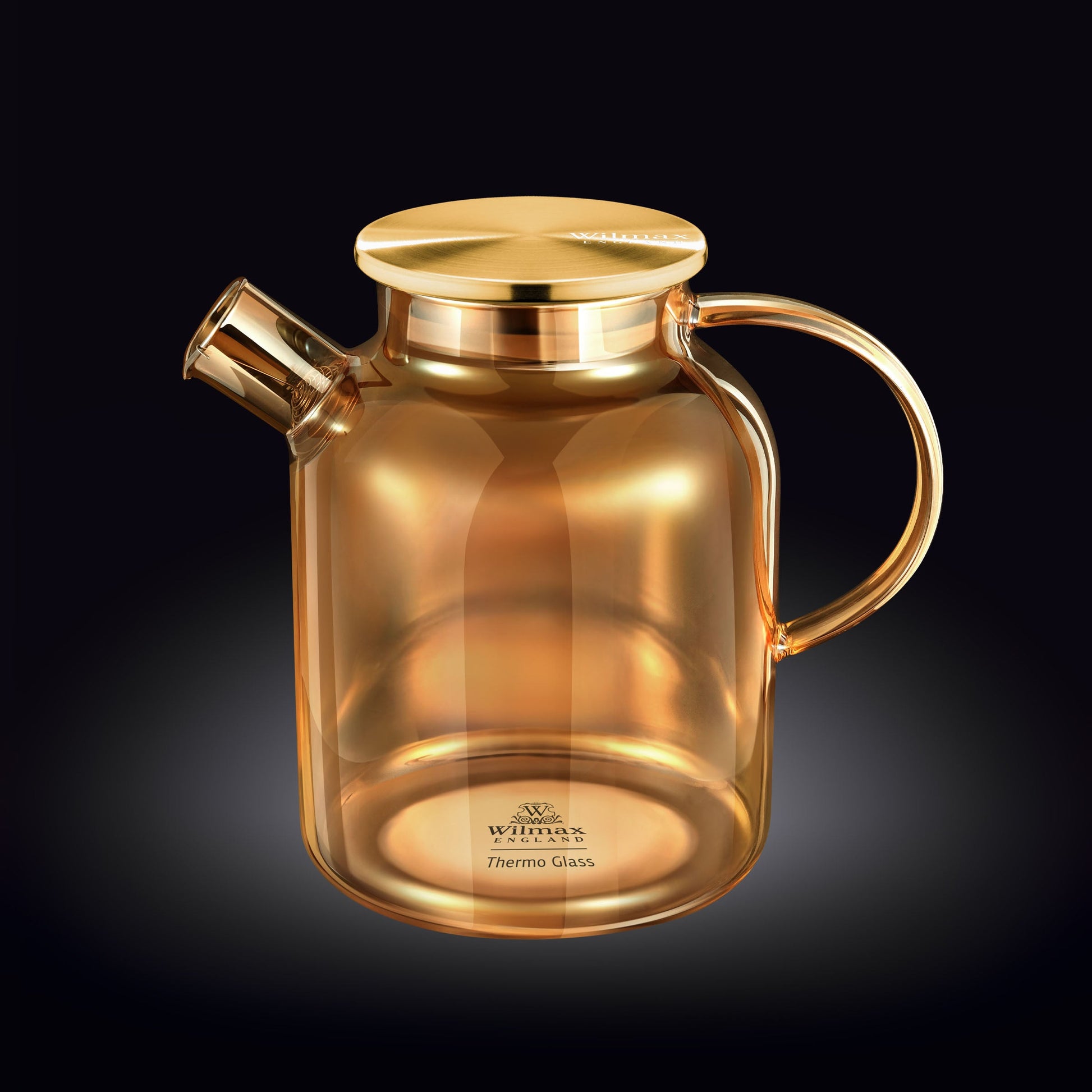 A clear glass teapot with a bamboo lid and stainless steel infuser, filled with golden-colored tea. The teapot has an ergonomic handle and is sitting on a wooden surface next to fresh tea leaves and a cup of tea.