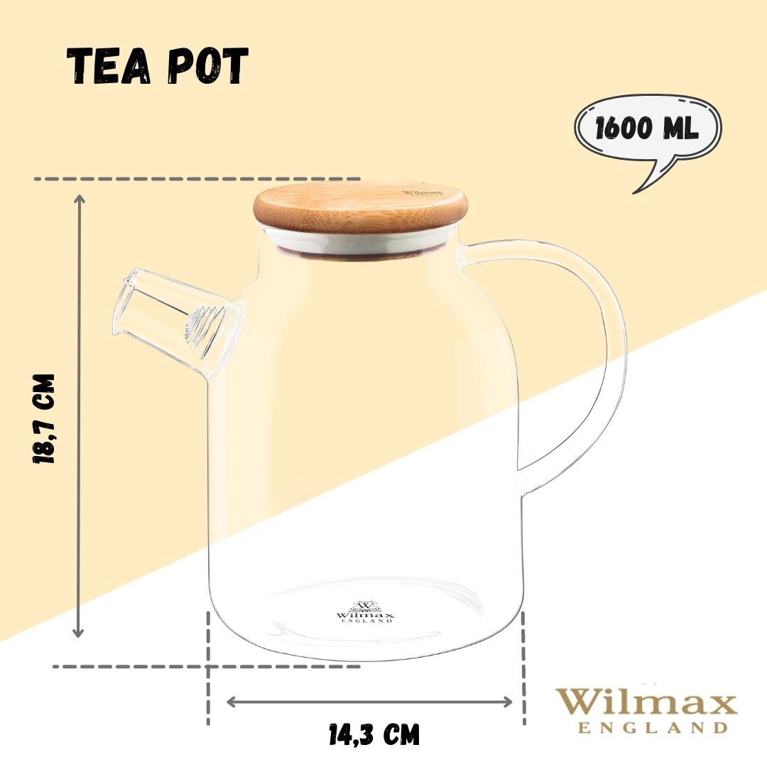 A clear glass teapot with a bamboo lid and stainless steel infuser, filled with golden-colored tea. The teapot has an ergonomic handle and is sitting on a wooden surface next to fresh tea leaves and a cup of tea.