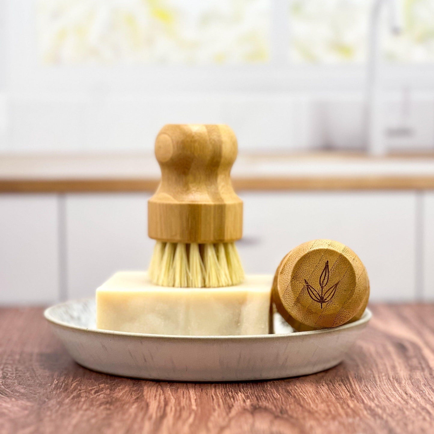 Bamboo pot brush with natural sisal bristles displayed with eco-friendly soap bar and wooden lid on rustic wooden surface - sustainable kitchen lifestyle