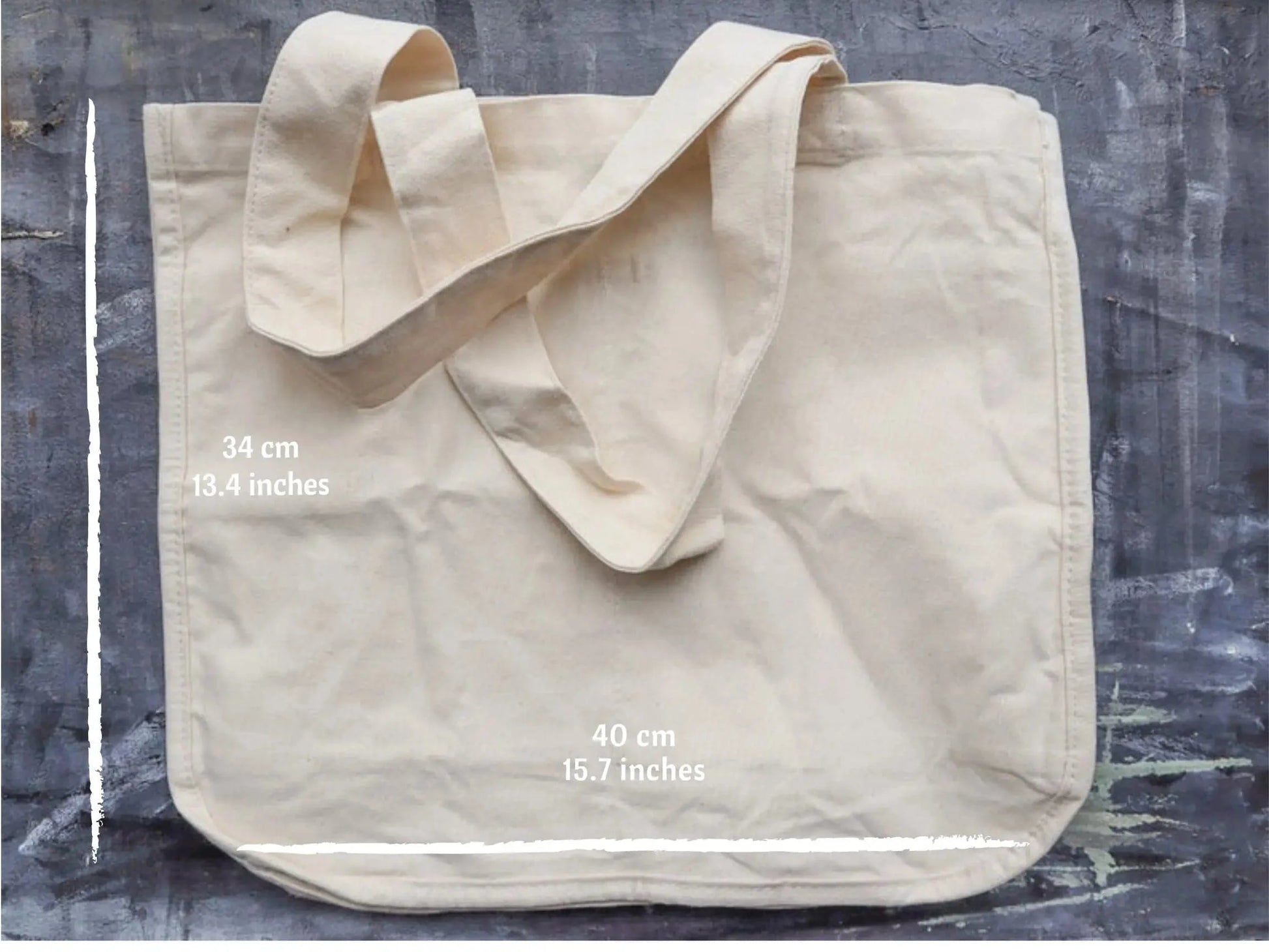 Beige tote bag with measurements on a textured gray background