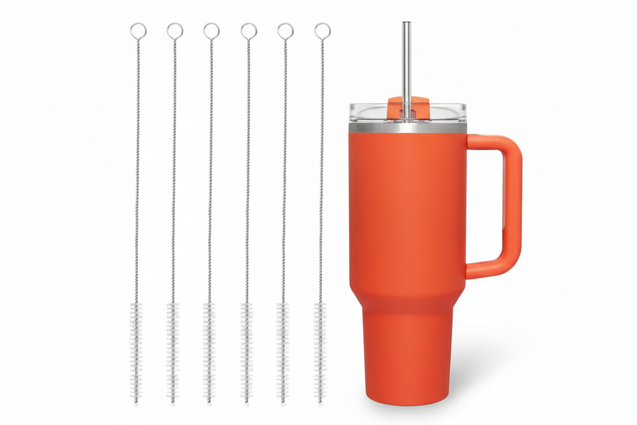 Orange mug with metal straw and cleaning brushes on a white background