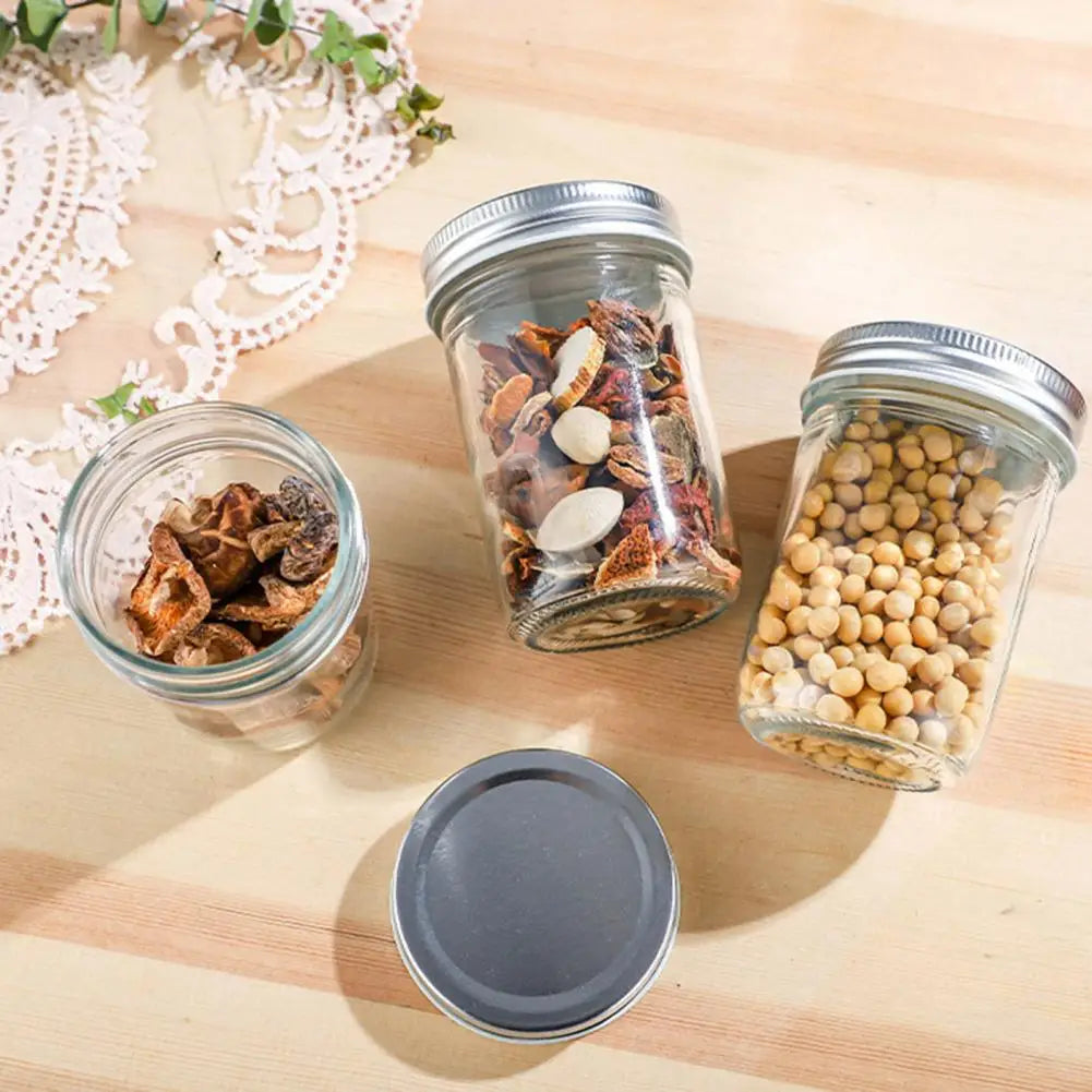 Three glass jars with metal lids on a wooden surface, containing various ingredients.