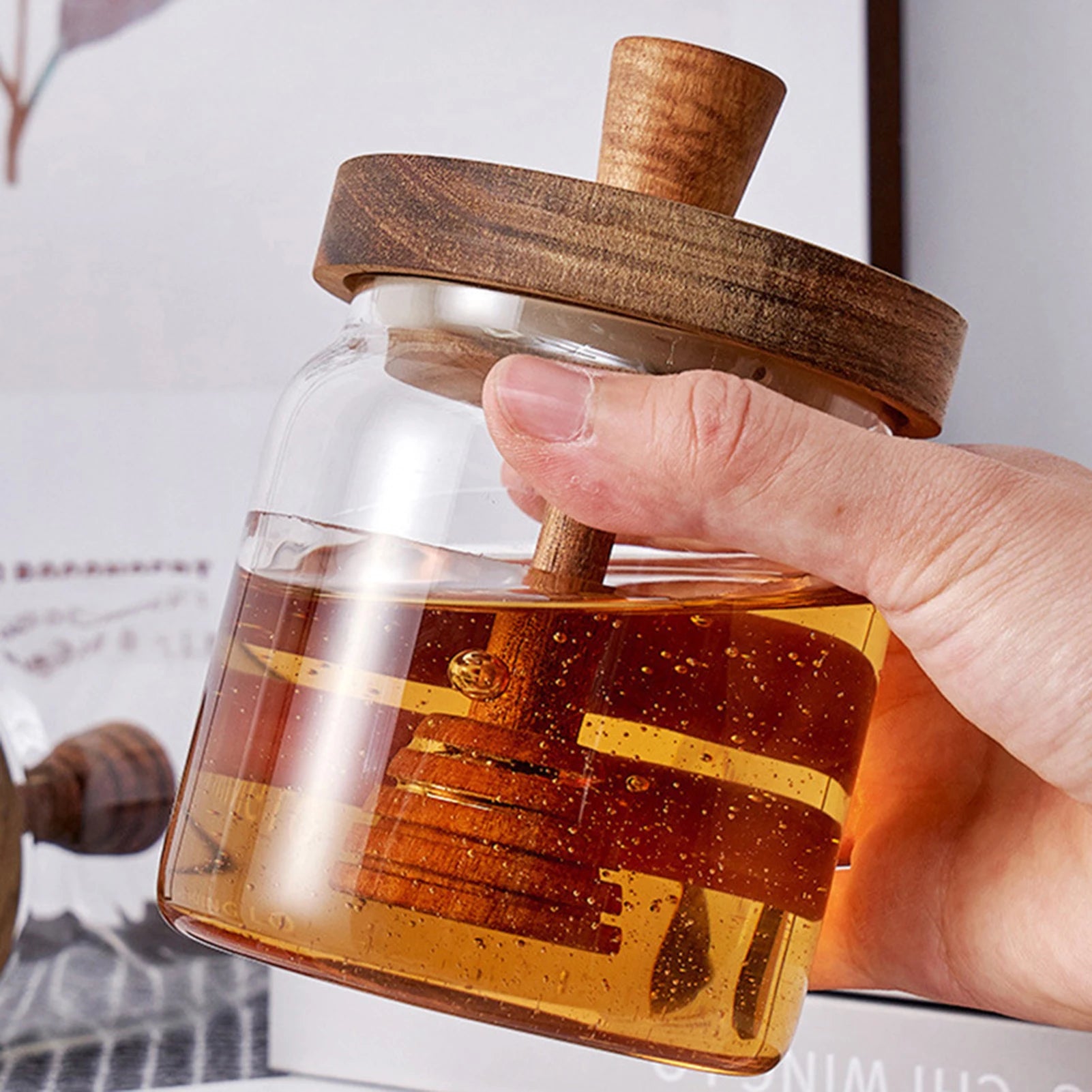 Hand holding a glass bottle with wooden lid and honeycomb design