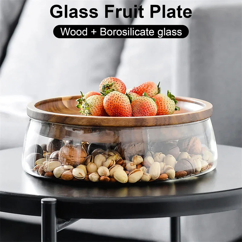 Glass fruit plate with wooden top containing strawberries and shells on a blurred background
