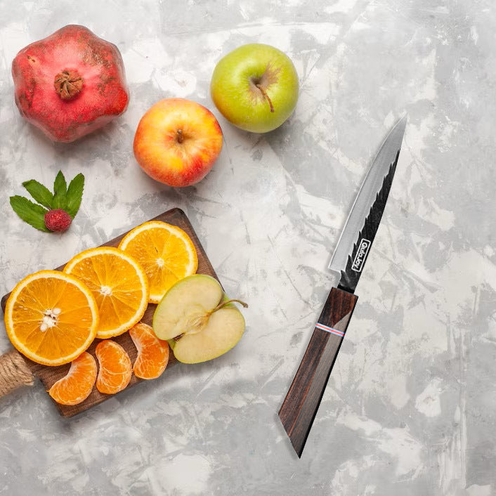 Fruits including oranges, apples, and a pomegranate on a cutting board with a knife on a gray surface.