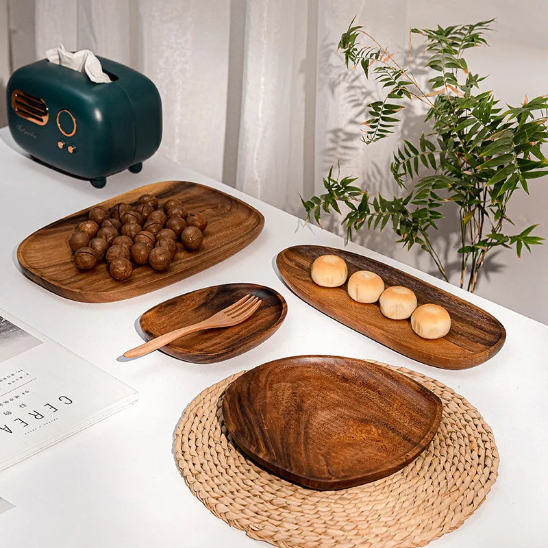 Set of wooden plates with food on a table with a plant in the background