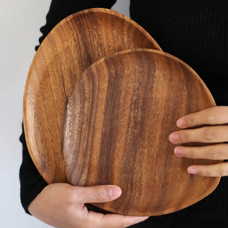 Two wooden plates held by a person against a neutral background
