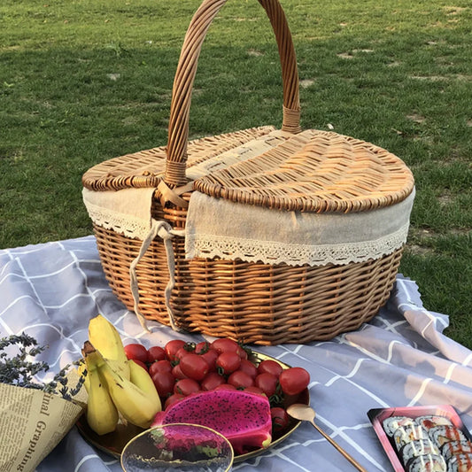 Wicker picnic basket with fruits and a blanket on grass