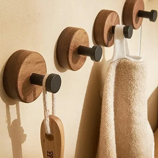 Wooden wall hooks with clothes hanging on a beige wall