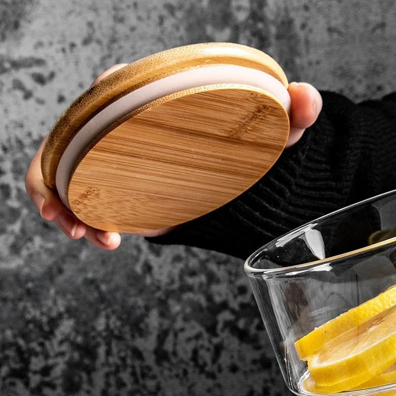 Wooden coasters held by a hand with a glass of lemon slices in the background