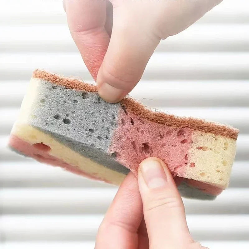 Two hands holding a layered cake with different colored layers against a white background