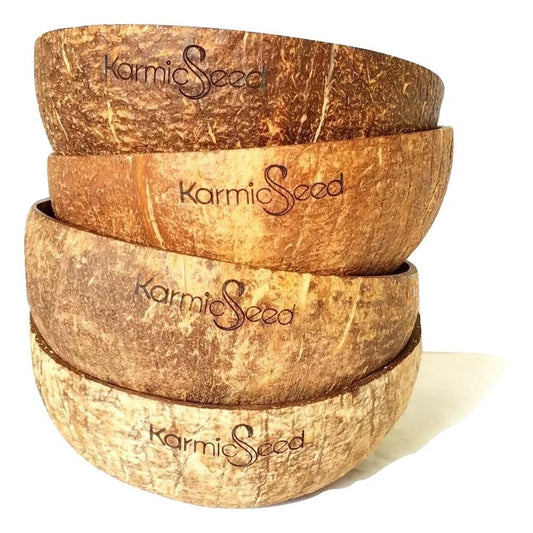 Four handcrafted coconut bowls on a natural wooden surface, surrounded by fresh tropical fruits. Each bowl has a smooth, polished finish with no branding or logo. Earthy and minimal.