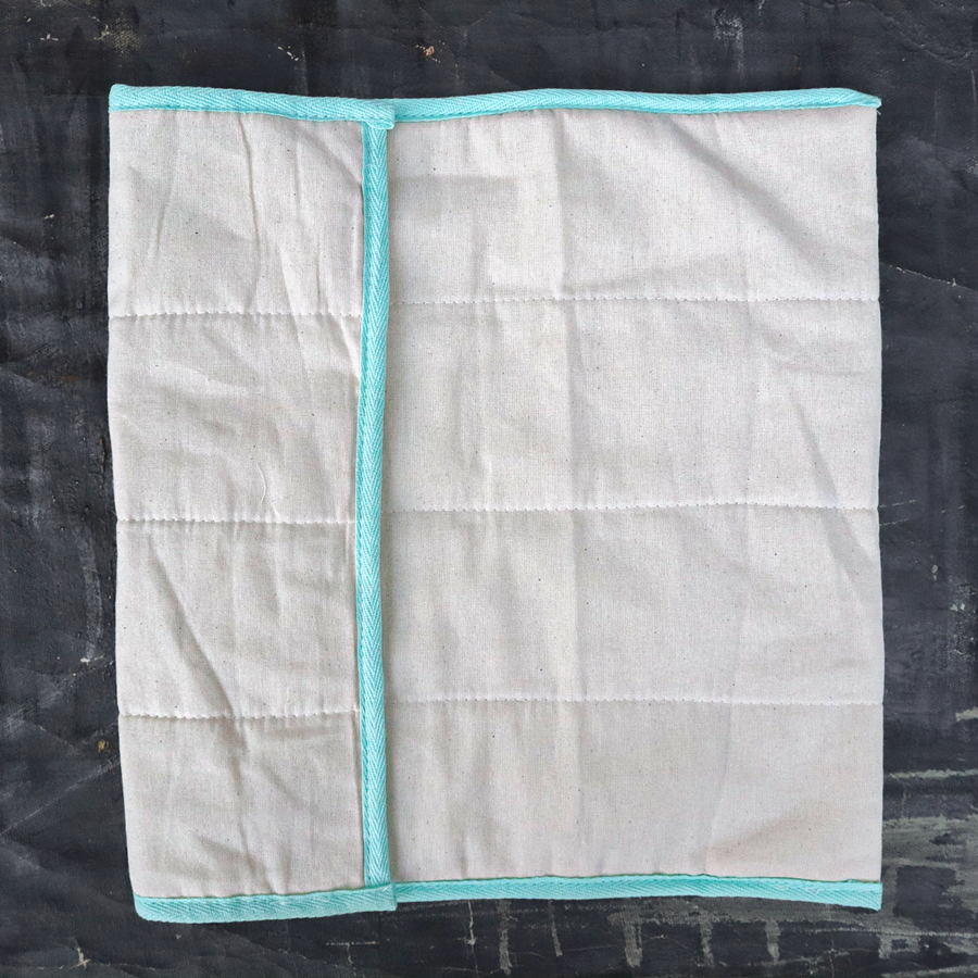 Gray quilt with teal border on a black background
