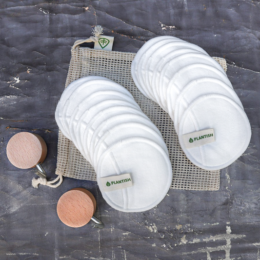 Reusable cotton facial rounds in white with Plantish branding, mesh laundry bag, and bronze makeup rounds on grey background