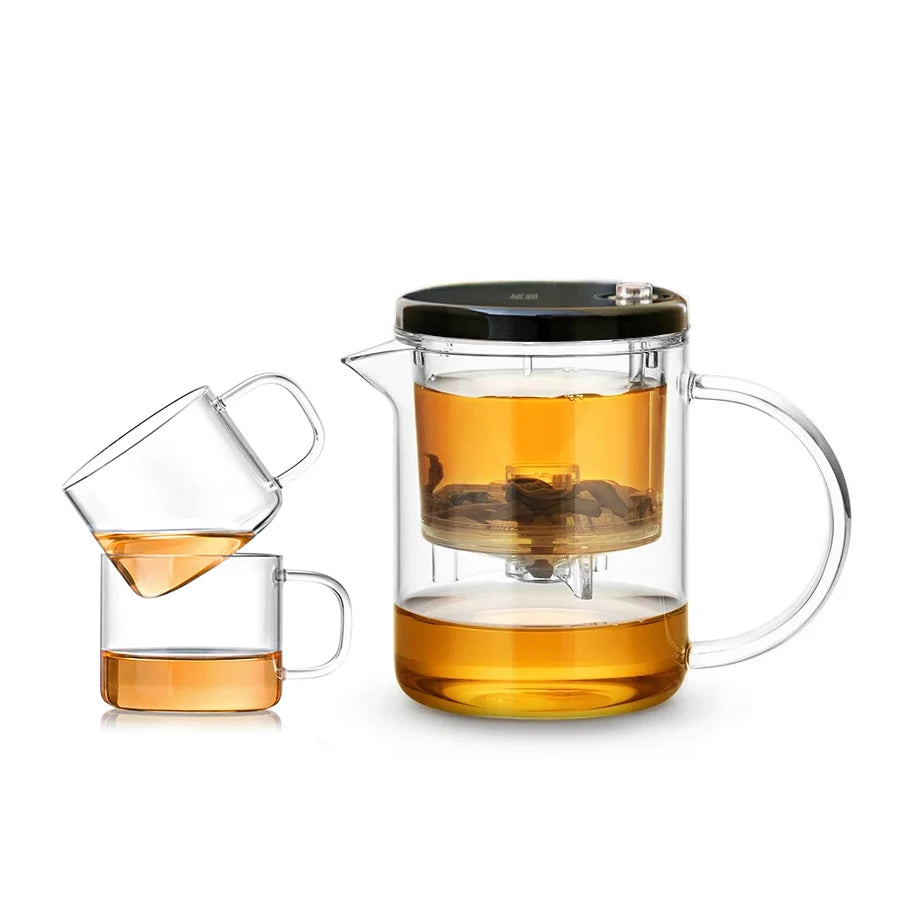 Clear glass tea set with a pitcher and cup filled with tea on a white background