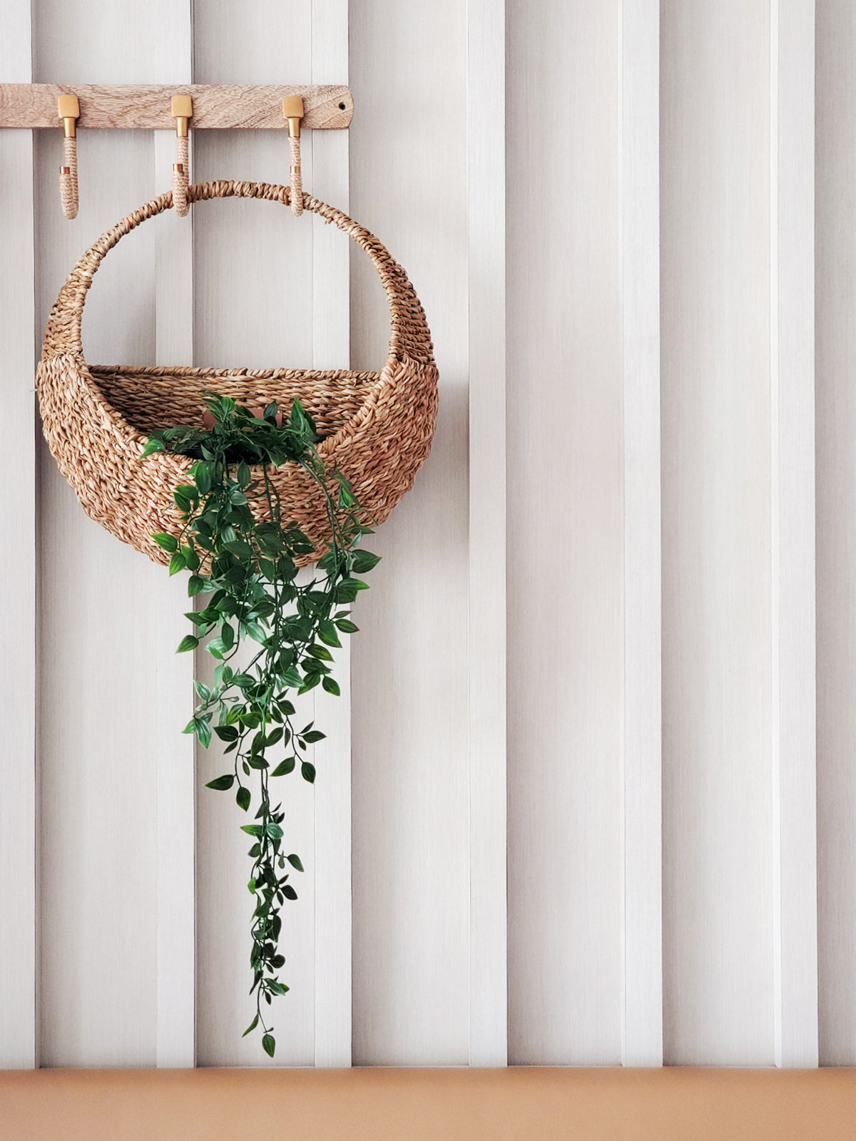 Savar woven seagrass wall hanging basket mounted on white striped wall with cascading green plant - lifestyle home decor photo