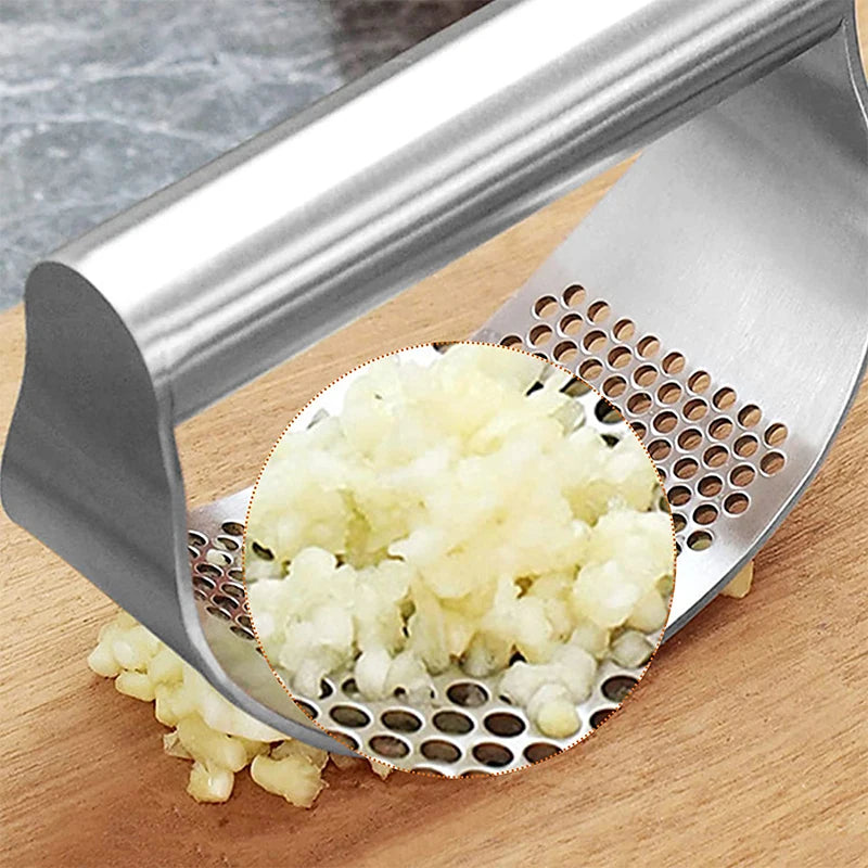 Metal garlic press with minced garlic on a wooden surface