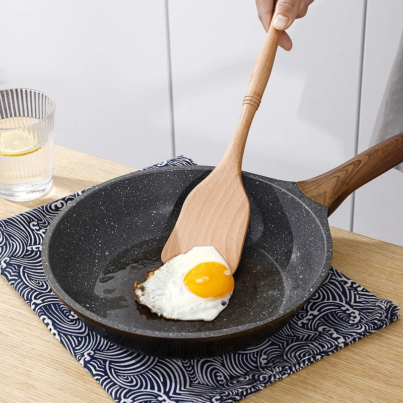 Natural wood kitchen utensils set including spatula and spoon for eco-friendly, non-stick cooking.