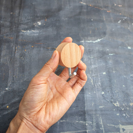 Hand holding a wooden hook against a dark textured background