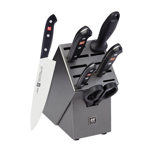 Knife set with black handles in a gray block on a white background